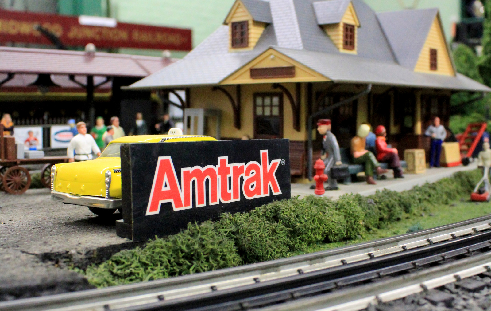 Model Amtrak sign with railroad station in the background.
