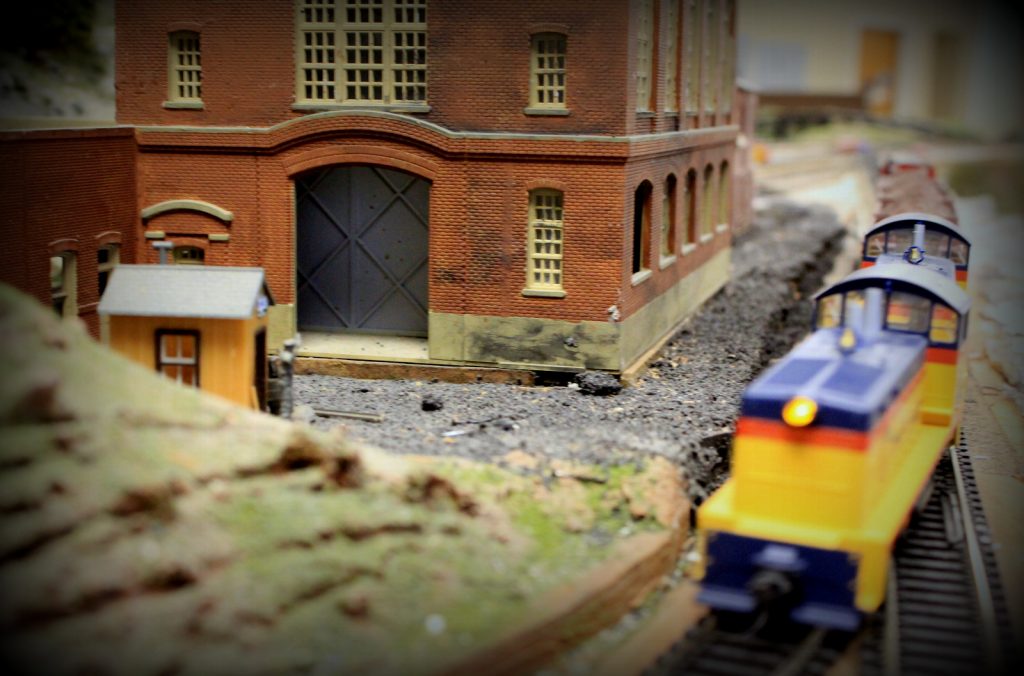 Brick building with Chessie locomotive cruising by - H-O Scale Model Railroad
