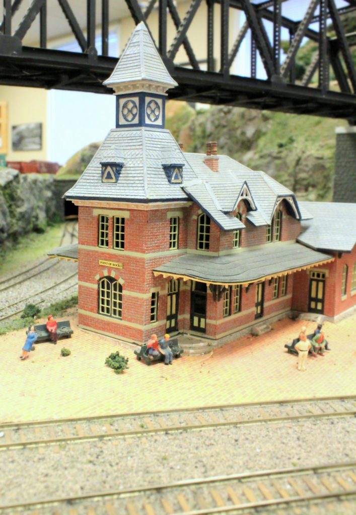 A model train station with railroad bridge overpass above it.