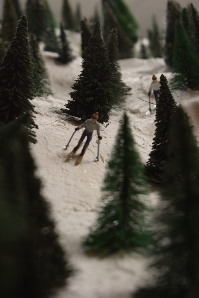 A snowy mountain scene with down-hill skiers - "Christmas at the Roundhouse" model train display.