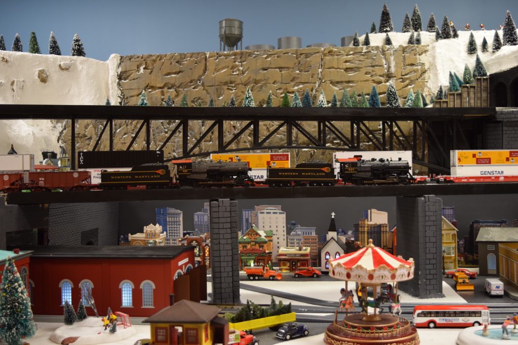 A train overpass and carnival scene in town - "Christmas at the Roundhouse" model train display.