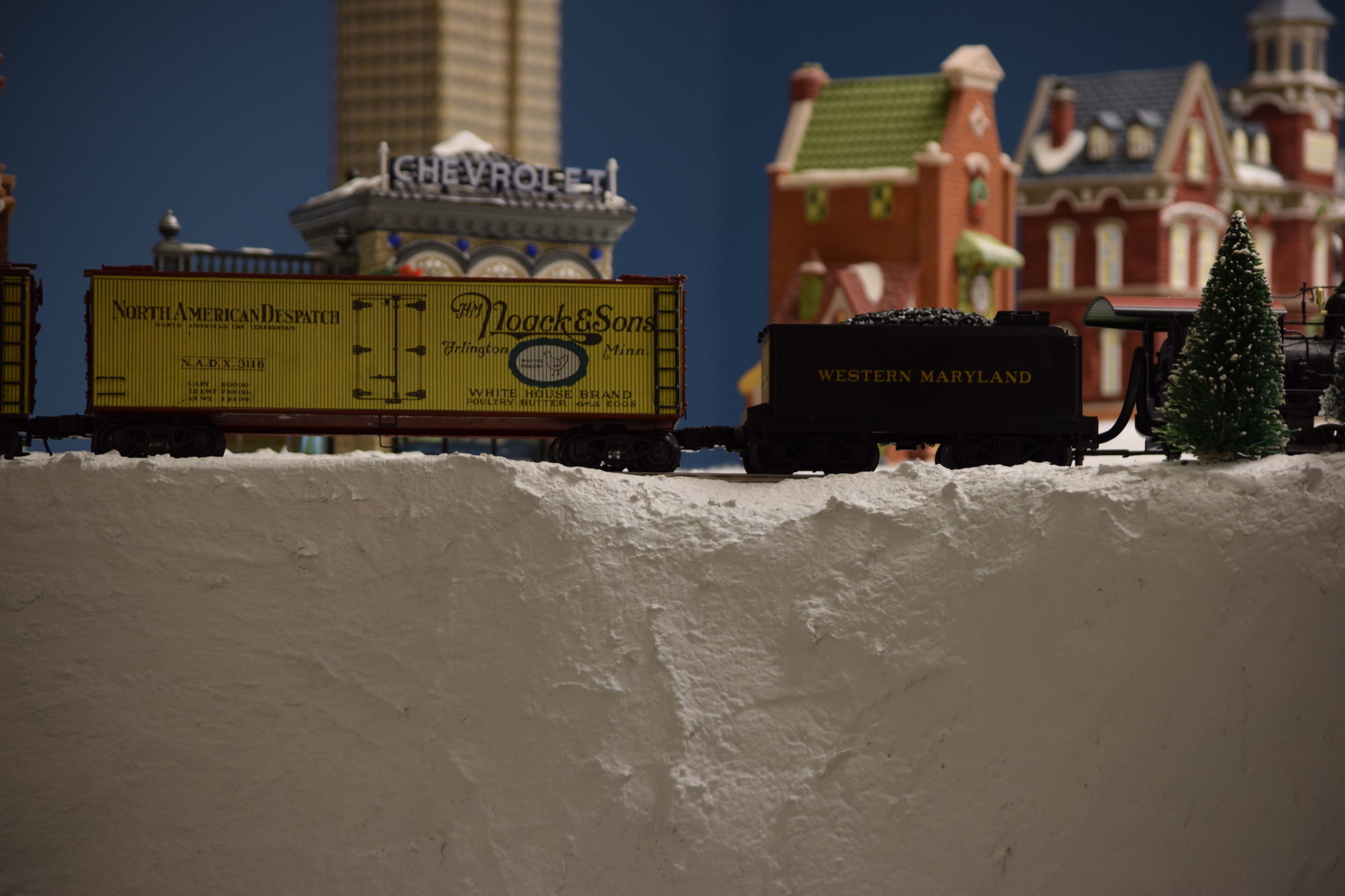 A mountain scene with a locomotive pulling freight cars on the mountain side - "Christmas at the Roundhouse" model train display.