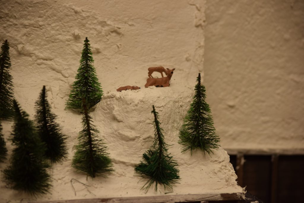 A snowy mountain scene with a deer family - "Christmas at the Roundhouse" model train display.
