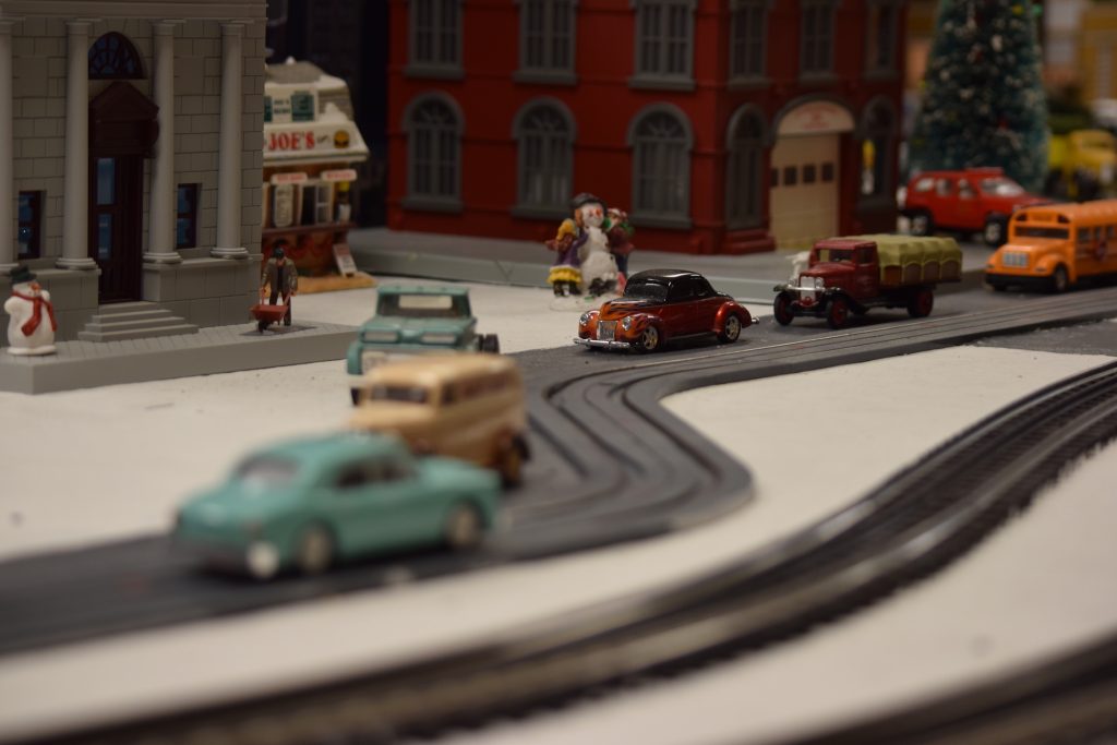 A street scene with people and automobiles in town - "Christmas at the Roundhouse" model train display.