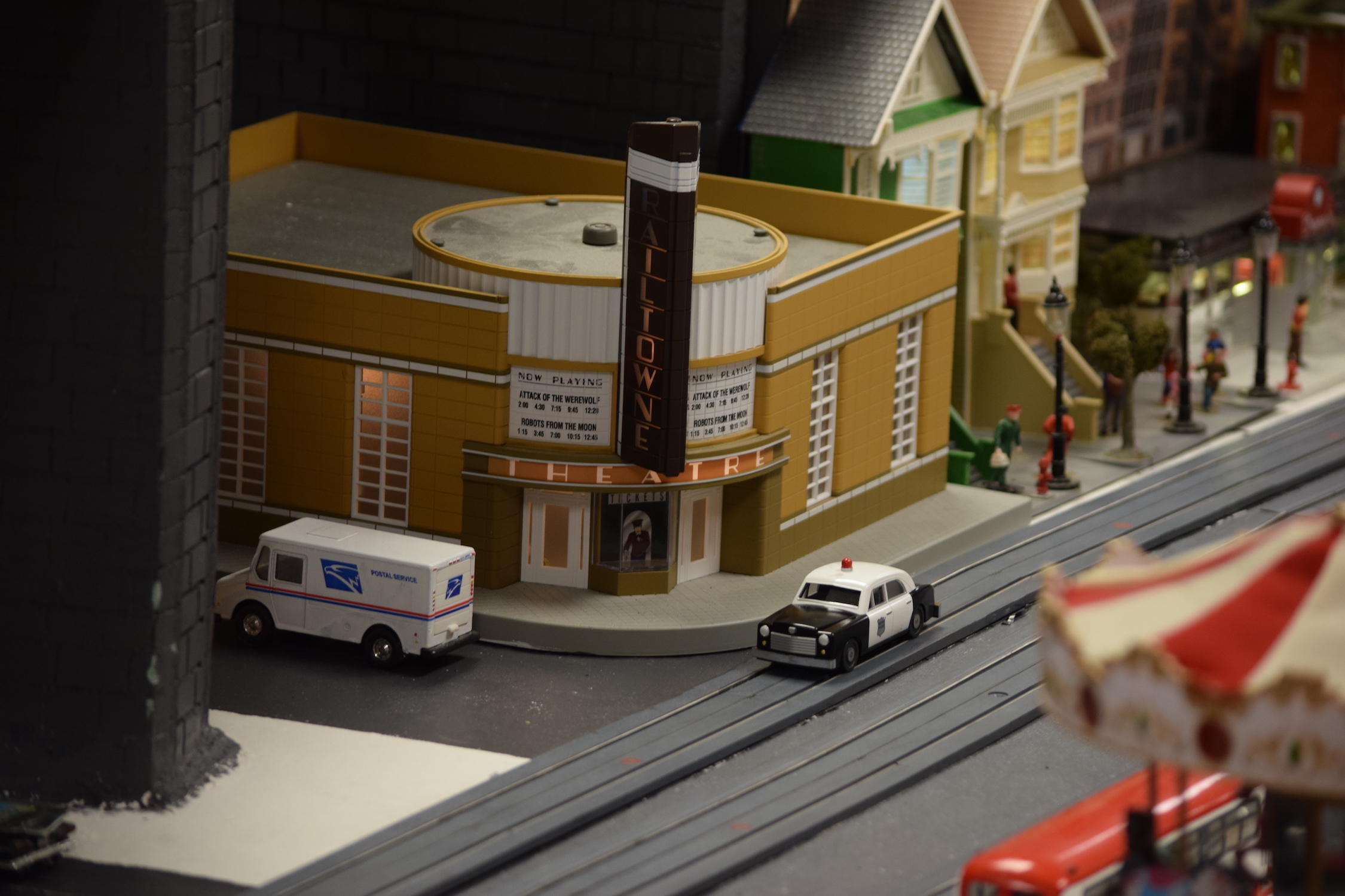 A movie theatre in town with a police car parked in front - "Christmas at the Roundhouse" model train display.