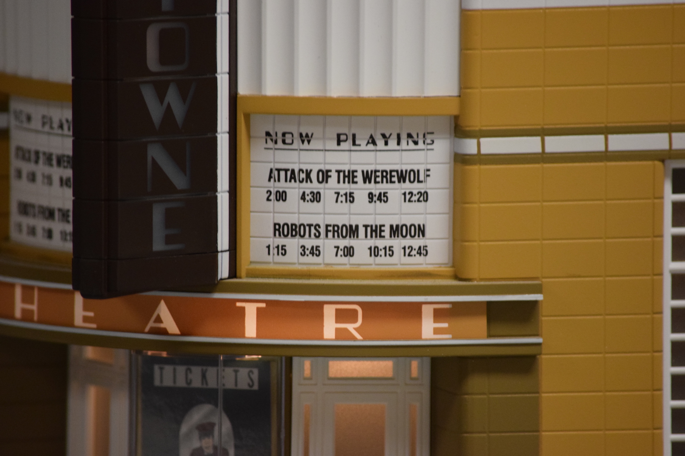 A close-up of the theatre sign that say’s “Now Playing, Attack of the Werewolf” and “Robots from the Moon” - "Christmas at the Roundhouse" model train display.