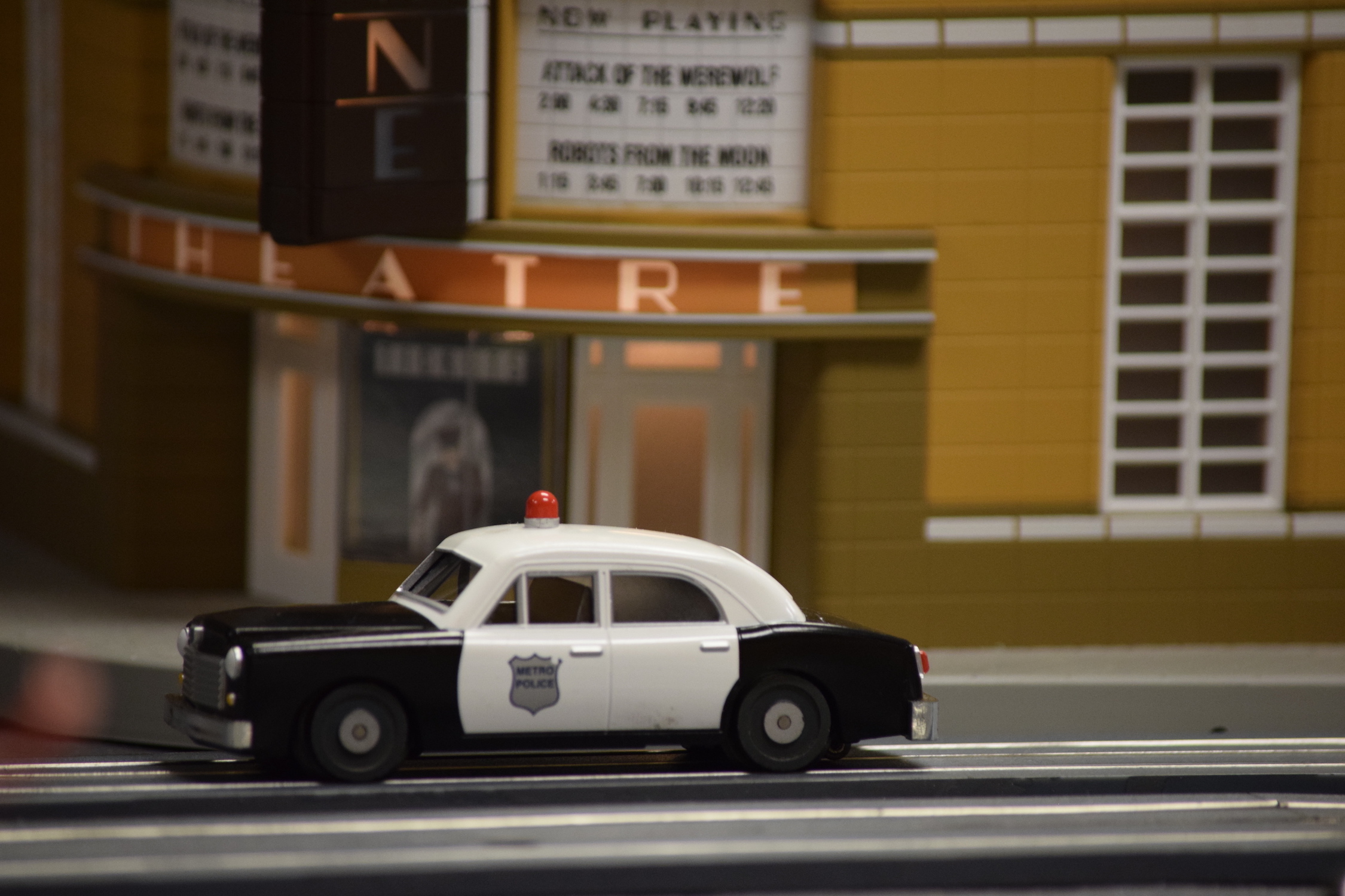 A movie theatre in town with a police car parked in front - "Christmas at the Roundhouse" model train display.
