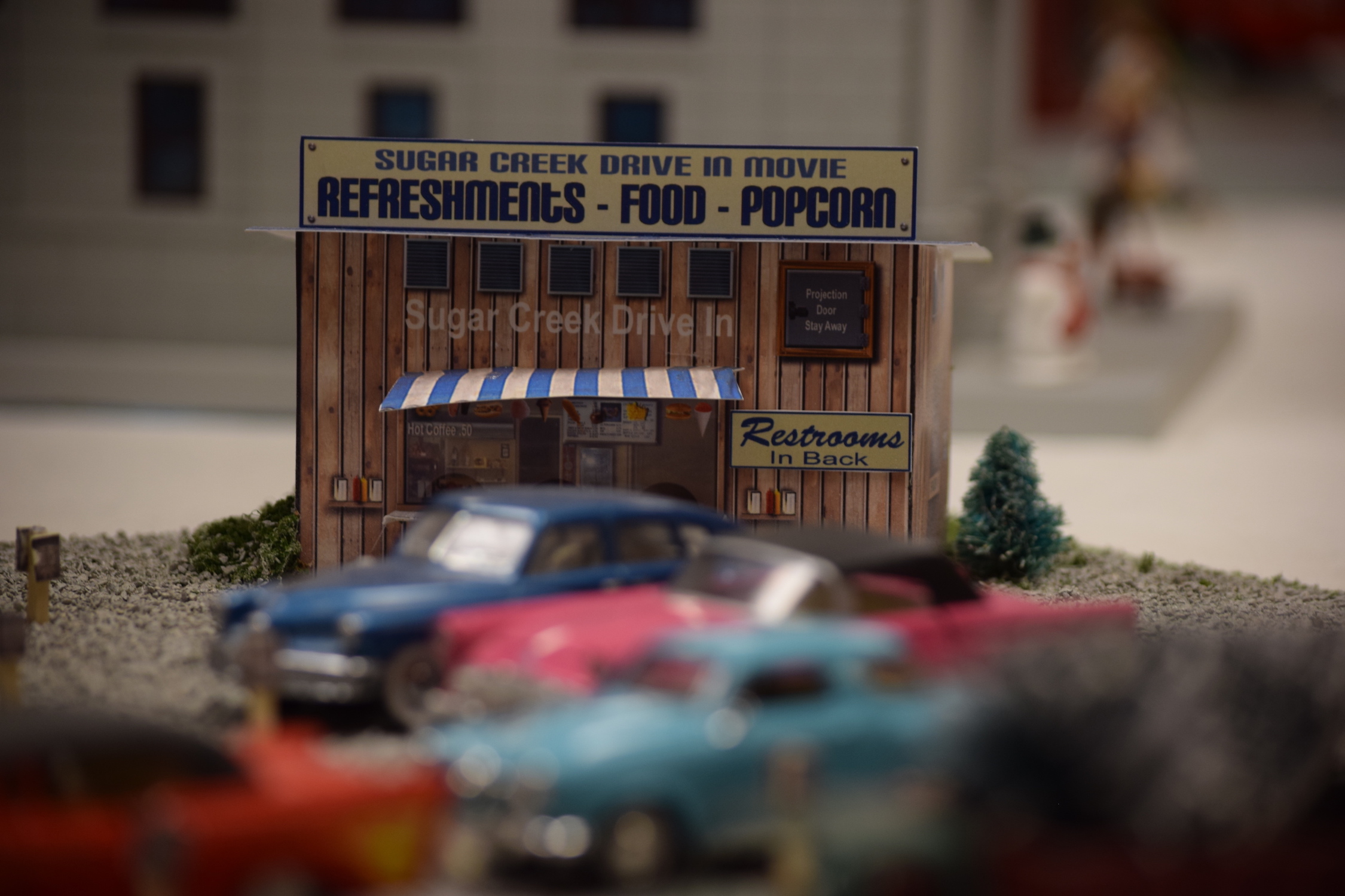 A drive-in movie scene with automobiles and a refreshment stand - "Christmas at the Roundhouse" model train display.
